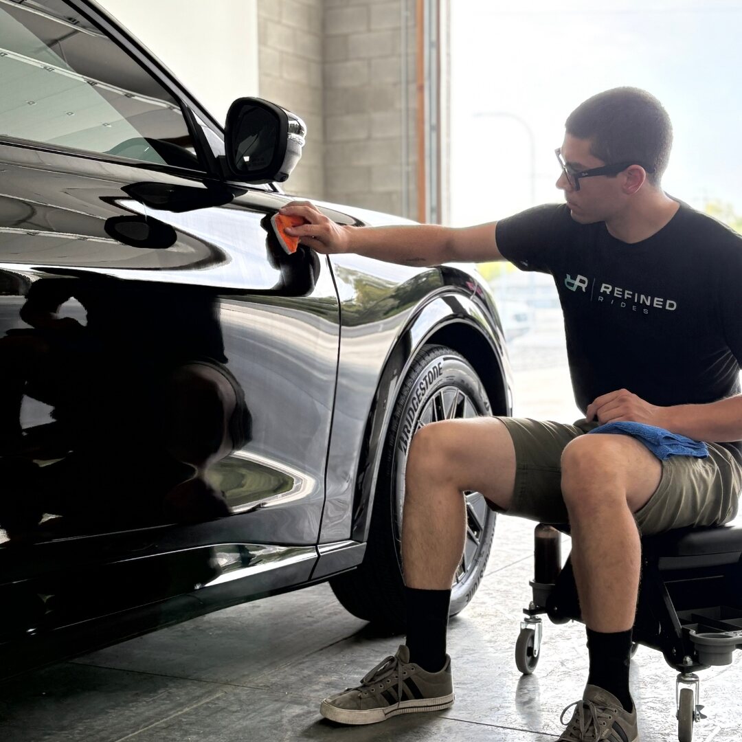 Refined Rides technician hand-applying ceramic coating to a black vehicle at the Yakima shop