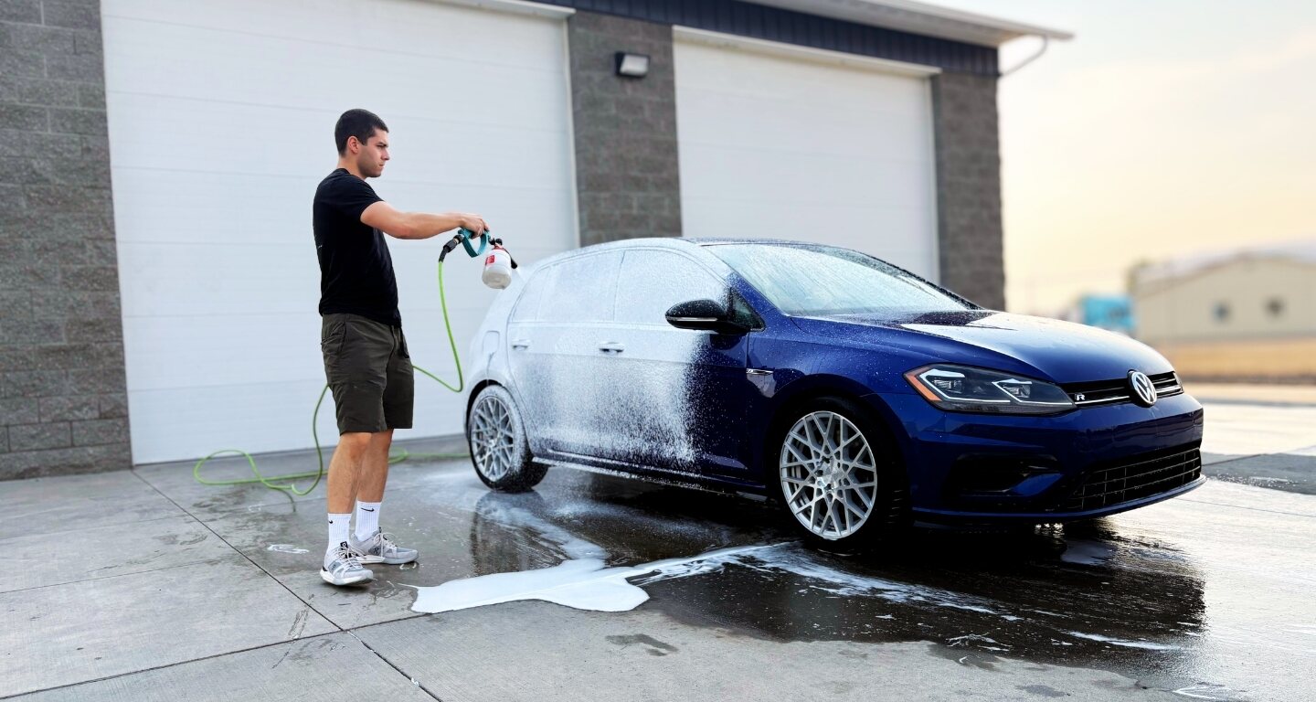 Refined Rides team member applying snow foam to a blue Volkswagen Golf R during a detail in Yakima, WA