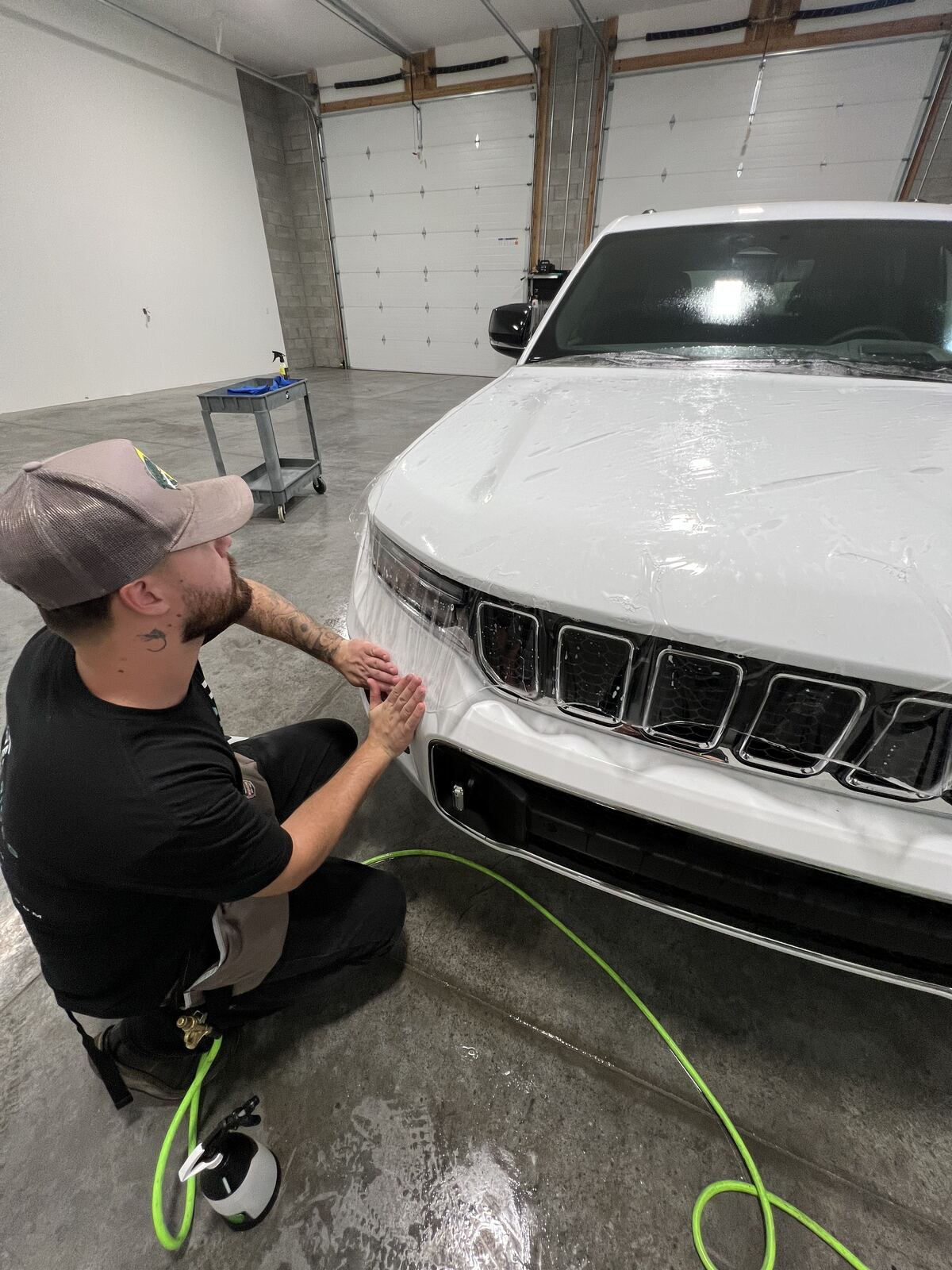 Refined Rides technician applying paint protection film to the front bumper of a white Jeep Grand Cherokee in Yakima, WA